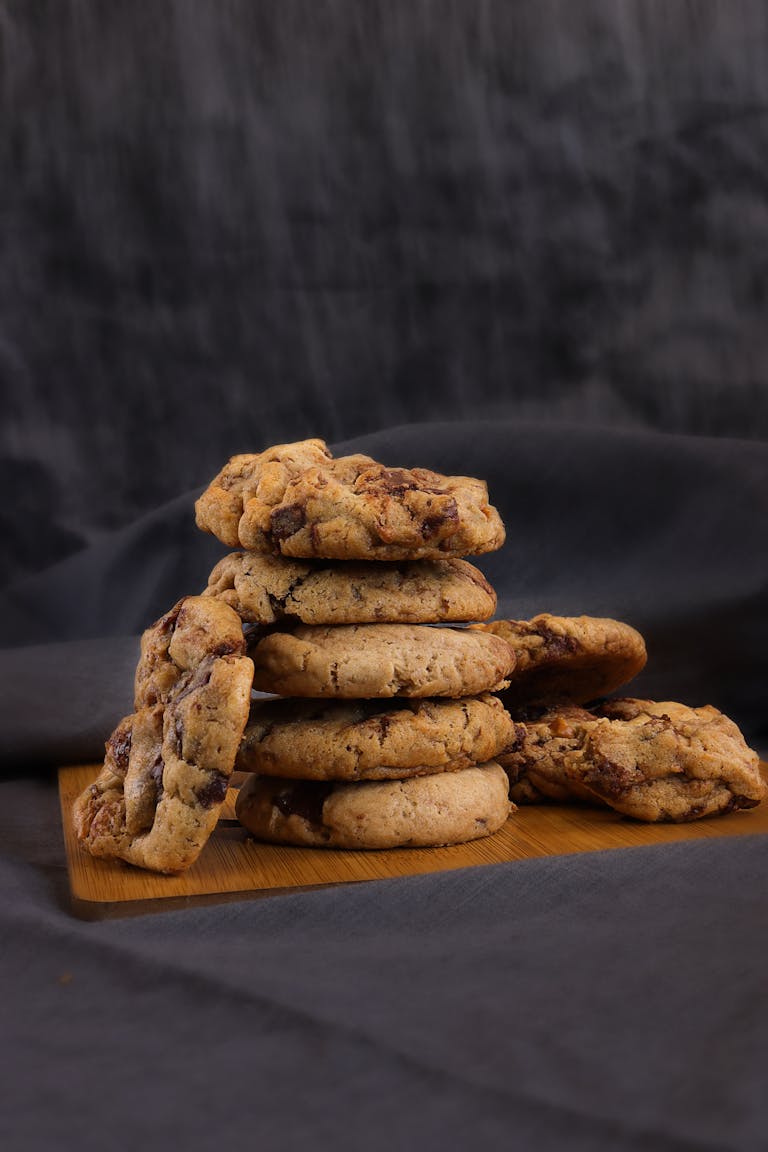Delicious homemade chocolate chip cookies stacked on a wooden board. Perfect for dessert lovers.